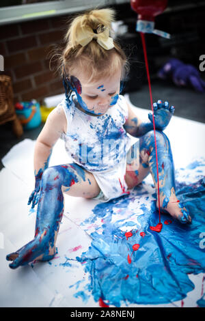 Eine entzückende kleine Kleinkind, Mädchen hat Spaß beim Spielen mit Farben malt, unordentlich und haben viel Spaß, in einer familiären Umgebung Schuß Stockfoto