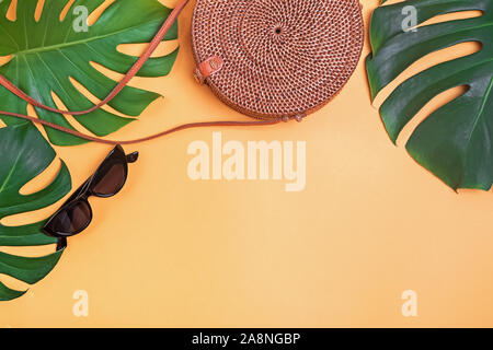 Kreative Sommer flach Komposition mit Rattan runde Tasche, Sonnenbrille und monstera Blätter Stockfoto