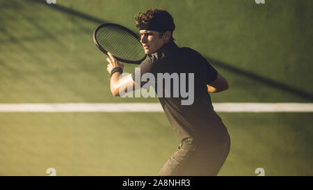 Junge Spieler Tennis spielen auf Hartplatz. Professional tennis player Schlagen einer Vorhand während eines Spiels. Stockfoto
