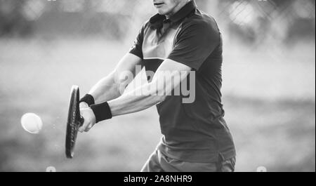 Schwarze und weiße Schuß eines männlichen Tennisspieler schlagen eine Rückhand während eines Spiels. Professionelle Spieler spielt am Tennisplatz. Stockfoto