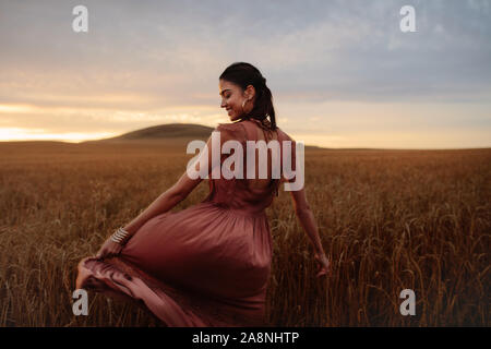 Junge Frau Gefühl glücklich auf dem Gebiet der Weizen bei Sonnenuntergang. Weibliche genießen Sie einen Tag in der Natur. Stockfoto