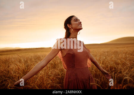 Glückliche Frau, die mit ihren ausgestreckten Armen in ein Weizenfeld. Weibchen mit einem Gefühl von Freiheit. Stockfoto