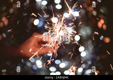 Hand mit einem brennenden Wunderkerzen Feuerwerk auf Licht bokeh Hintergrund. Neues Jahr und Weihnachten Konzept. Stockfoto