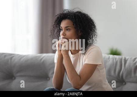 Afrikanische amerikanische Frau denken über das Problem alleine Zuhause umgekippt Stockfoto