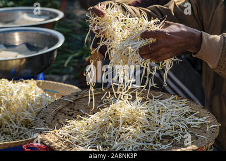 Ein Mann wirft frische Soja sojasprossen am lokalen Markt in Kalaw, Myanmar (Birma). Stockfoto