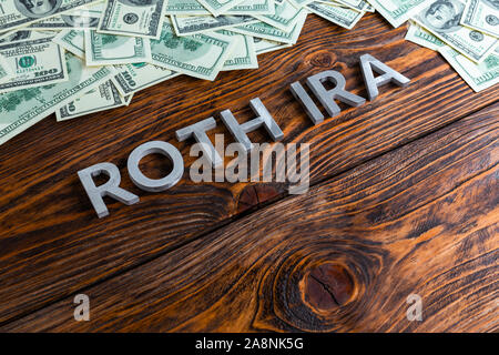 Worte ROTH IRA auf Holz- Oberfläche mit Metall Buchstaben us Papiergeld Stockfoto