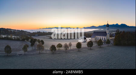 Schönen nebeligen Herbstmorgen in Bayern - Luftaufnahme von Wilparting Kirche vor der Alpen im Chiemgau Stockfoto
