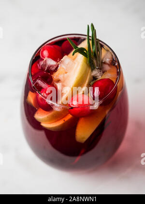 Winter Sangria auf der Tischplatte mit grau Leinen Tischdecke. Gläser Sangria mit Obst schneiden, Cranberry und Rosmarin. Vertikale. Stockfoto