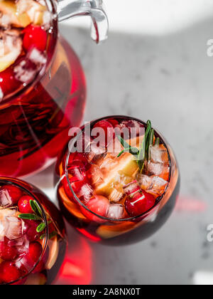 Winter Sangria auf der Tischplatte mit grau Leinen Tischdecke. Gläser Sangria mit Obst schneiden, Cranberry und Rosmarin. Kopieren Sie Platz für Text oder Design. Top View oder flach. Vertikale. Stockfoto