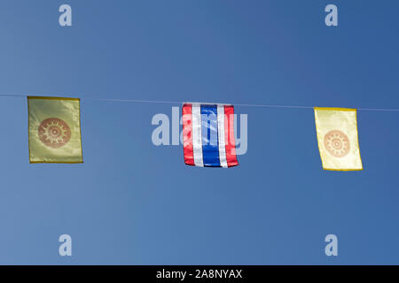 Vor blauem Himmel in Thailand gesehen, die roten, weißen und blauen Flagge und die gelben und roten dharma Rad Flagge der thailändischen Buddhismus Stockfoto