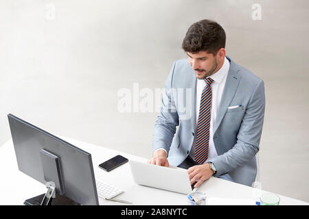 High Angle Shot der Unternehmer tragen Anzug beim Sitzen am Schreibtisch und Arbeiten am Notebook. Stockfoto