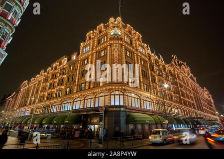 Außenansicht des Kaufhaus Harrods in London bei Nacht im Winter. Nacht Verkehr Straße Landschaft in einem typischen regnerischen Tag. Stockfoto