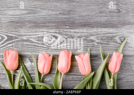 Eine Reihe von mehreren rosa Tulpen auf grauen Brettern. Stockfoto