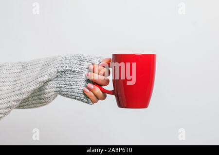 Woman's Hand in gemütlichen Pullover rote Kaffeetasse. Stockfoto