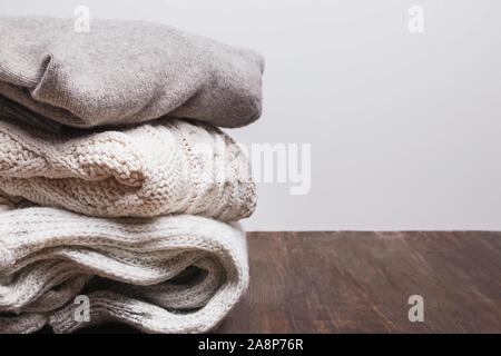 Stapel von warmen gestrickten Pullover auf dem hölzernen Tisch Stockfoto
