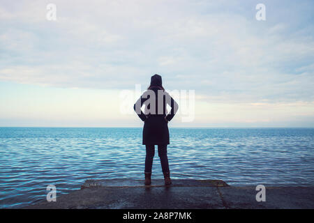 Rückansicht der Frau am Meer im Winter saison, stolze junge Dame suchen den Horizont Stockfoto