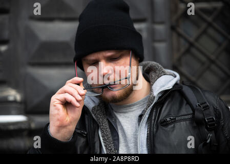 Mann im Ledermantel Brillen Holding Stockfoto