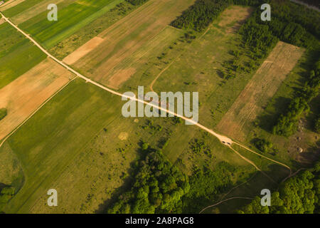 Drone Ansicht der landwirtschaftlichen Wiese mit einer Straße durch. Stockfoto