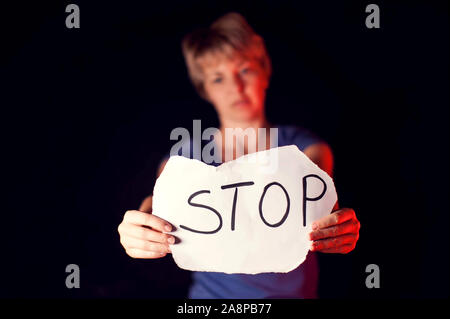 Frau hält Papier mit Nachricht ihr vor schwarzem Hintergrund zu helfen. Menschen, Gewalt in der Familie, Kriminalität Konzept Stockfoto