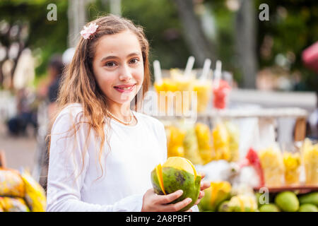 Schöne junge Mädchen am Paseo Bolivar Square in der Stadt Cali Essen tropische Früchte in Kolumbien Stockfoto