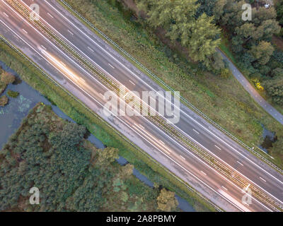 Luftaufnahme der vierspurigen Autobahn mit Seitenstreifen und moderater Verkehr bei Sonnenuntergang Stockfoto