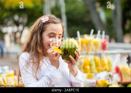 Schöne junge Mädchen am Paseo Bolivar Square in der Stadt Cali Essen tropische Früchte in Kolumbien Stockfoto