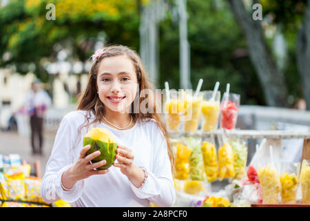 Schöne junge Mädchen am Paseo Bolivar Square in der Stadt Cali Essen tropische Früchte in Kolumbien Stockfoto