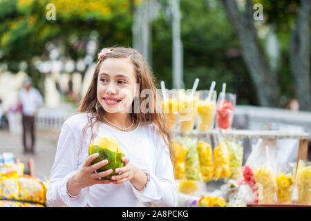 Schöne junge Mädchen am Paseo Bolivar Square in der Stadt Cali Essen tropische Früchte in Kolumbien Stockfoto