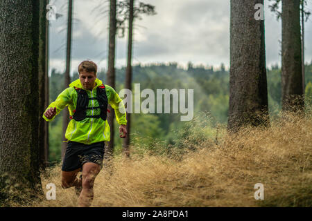 Ein junger Athlet in Barfuß Schuhe läuft den Berg hinunter. Die Berge laufen. Querfeldein laufen. Einzelnen Sport Stockfoto