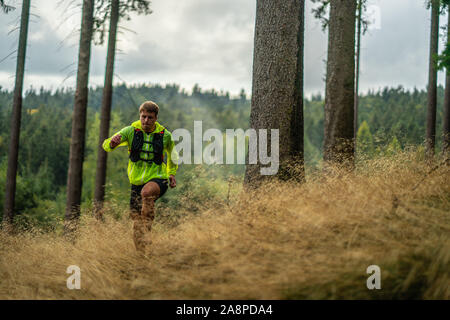 Ein junger Athlet in Barfuß Schuhe läuft den Berg hinunter. Die Berge laufen. Querfeldein laufen. Einzelnen Sport Stockfoto