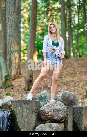 Mädchen walking im Park entlang Steine umgebende künstliche Creek Stockfoto