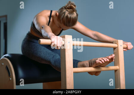 Schöne positive blonde Frau wird vorbereitet, die Pilates Übung, Training auf Fass Ausrüstung. Fitness Concept, spezielle Fitnessgeräte Stockfoto