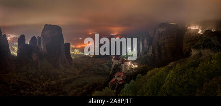 Berge und Klöster von Meteora nachts beleuchtet über Kastraki Stadt glühende im fernen Nebel Stockfoto