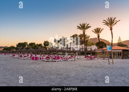 Mallorca, Spanien - 5. Mai 2019: Liegen mit Sonnenschirmen am Strand Playa de Alcudia auf Mallorca, Spanien Stockfoto