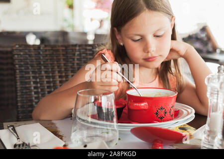 Kleine blonde Kaukasische Mädchen isst eine Suppe in einem Restaurant im Sommer Tag, Nahaufnahme portrait Stockfoto