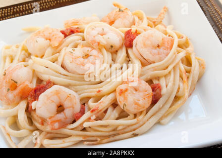 Hausgemachte Shrimp Scampi serviert auf einem Bett von Linguini pasta Nudeln. Doppelte eckige Platten in weißen und braunen Farben. Stockfoto