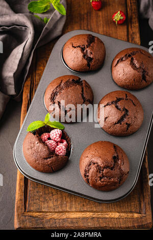 Chocolate Muffins mit Himbeeren in Metall muffin Backform, Ansicht von oben, vertikale Ausrichtung Stockfoto