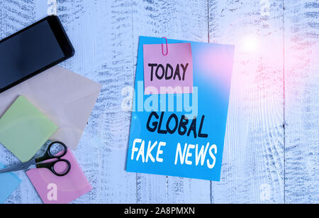 Schreiben Hinweis angezeigt Globale gefälschte Nachrichten. Business Konzept für falsche Informationen Journalismus liegt Desinformation Hoax Umschlag Papier smartphone Hinweis Stockfoto