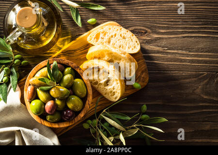 Oliven, Olivenöl und Ciabatta auf hölzernen Tisch. Stockfoto