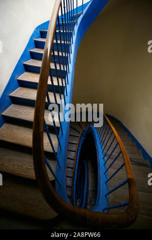 Abstrakter Blick auf die ovale Treppe mit verwitterten Holzstufen und schattigen Wänden Stockfoto