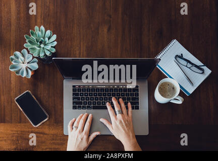 Ansicht der Frau Hände Arbeiten am Laptop an den hölzernen Tisch. Stockfoto