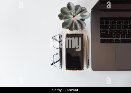 Ansicht von oben von Arbeitsbereich mit Laptop, Handy, Brille und Stift. Stockfoto