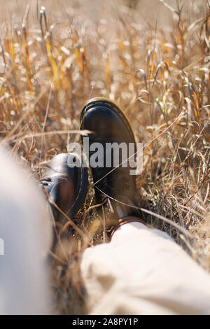 Weibliche Füße in schwarzem Leder Stiefel auf Gras Stockfoto