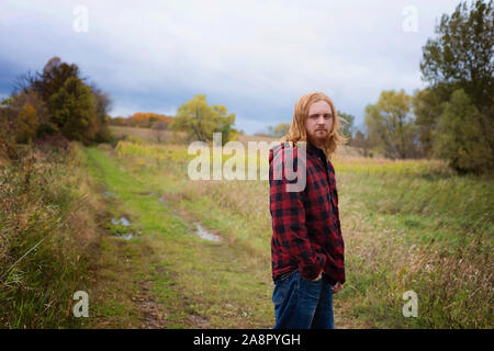 Junger Mann mit langen roten Haaren und Bart außerhalb im Land Stockfoto