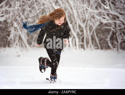 Junge Rothaarige Mädchen spielen im Freien im Schnee Stockfoto