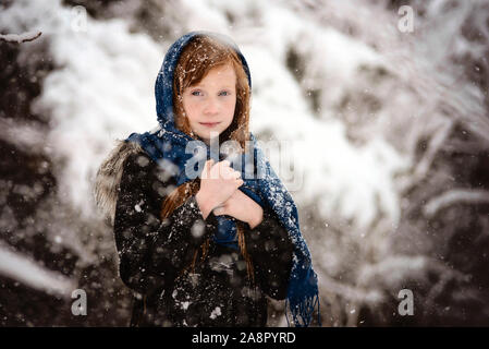 Junge Rothaarige Mädchen spielen im Freien im Schnee Stockfoto