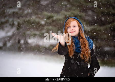 Junge Rothaarige Mädchen spielen im Freien im Schnee Stockfoto