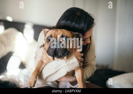 Eine tätowierte Frau, die Ihre cute puppy umarmte. Glücklicher Moment zwischen Pe Stockfoto