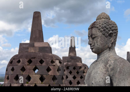 Ein Buddah in seinem Stupa von borobodur mit Blick auf das umliegende Land und wacht über die Vulkane. Einige von ihnen werden während der trockenen Jahreszeit geöffnet. Eine stun Stockfoto