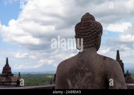 Ein Buddah in seinem Stupa von borobodur mit Blick auf das umliegende Land und wacht über die Vulkane. Einige von ihnen werden während der trockenen Jahreszeit geöffnet. Eine stun Stockfoto